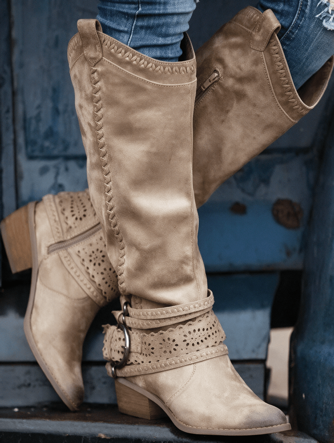 The Sloane Boots in taupe suede — tall cut-out harness boot on rustic blue steps